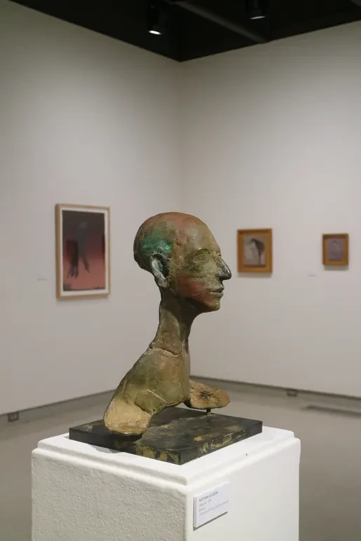 Fresno Art Museum — bronze bust sculpture on white pedestal with framed paintings in background