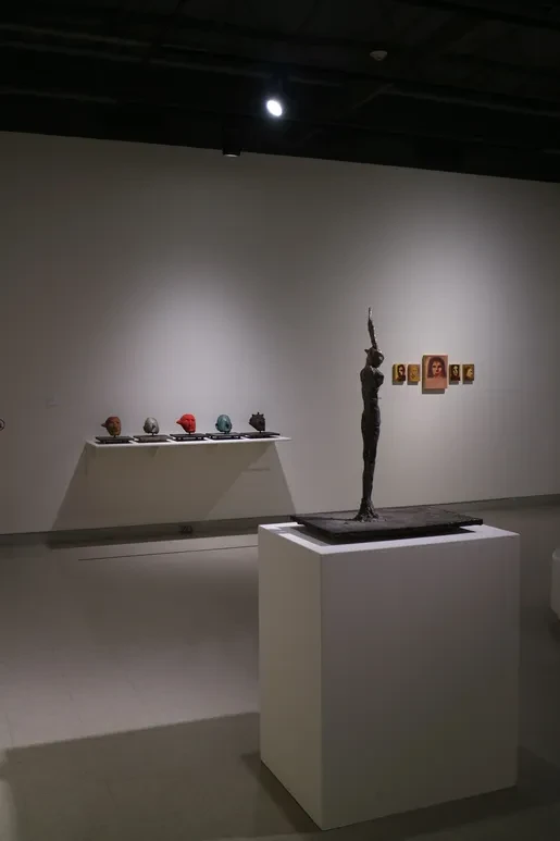 Fresno Art Museum — painted heads on shelf with tall bronze figure and portrait photographs